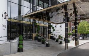 uma fachada de um edifício com escadas e vasos de plantas em Conrad Dublin em Dublin