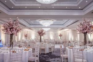 un salón de banquetes con mesas y sillas blancas y flores rosas en Conrad Dublin, en Dublín