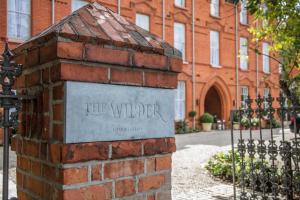 een bakstenen pilaar met een opzettelijk bord voor een gebouw bij The Wilder in Dublin