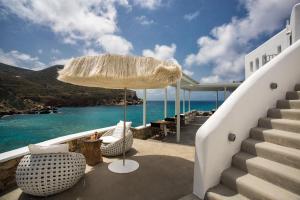 a patio with chairs and an umbrella and the ocean at Blue Sand Boutique Hotel & Suites in Agali