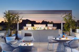 a rooftop patio with chairs and tables and a bar at Palazzo Montemartini Rome, A Radisson Collection Hotel in Rome