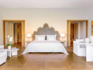 a bedroom with a large white bed with white furniture at Corfu Imperial, Grecotel Beach Luxe Resort in Kommeno