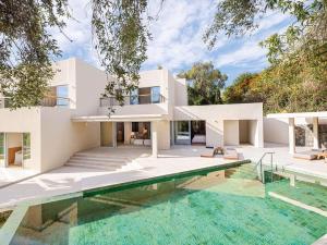 une maison avec une piscine en face de celle-ci dans l'établissement Corfu Imperial, Grecotel Beach Luxe Resort, à Komméno