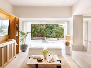 a living room with two beds and a table at Corfu Imperial, Grecotel Beach Luxe Resort in Kommeno