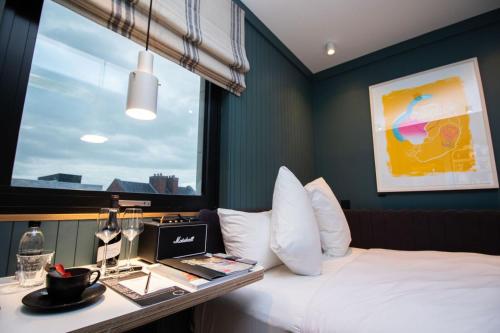 a hotel room with a bed and a desk with a laptop at The Devlin Dublin in Dublin