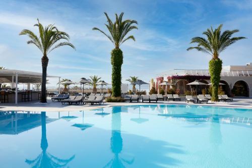 a large swimming pool with palm trees and chairs at MarBella, Mar-Bella Collection in Agios Ioannis Peristeron