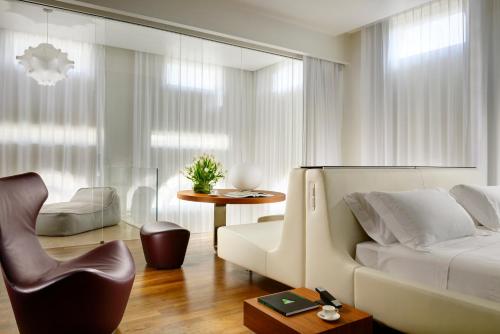 a living room with a white bed and a chair at Palazzo Montemartini Rome, A Radisson Collection Hotel in Rome