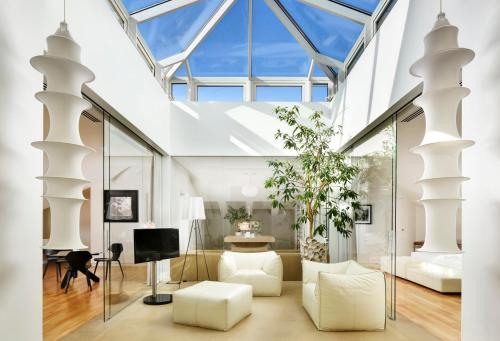 a living room with white furniture and a glass ceiling at Palazzo Montemartini Rome, A Radisson Collection Hotel in Rome