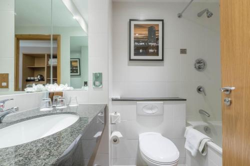 a white bathroom with a toilet and a sink at Clayton Hotel Ballsbridge in Dublin