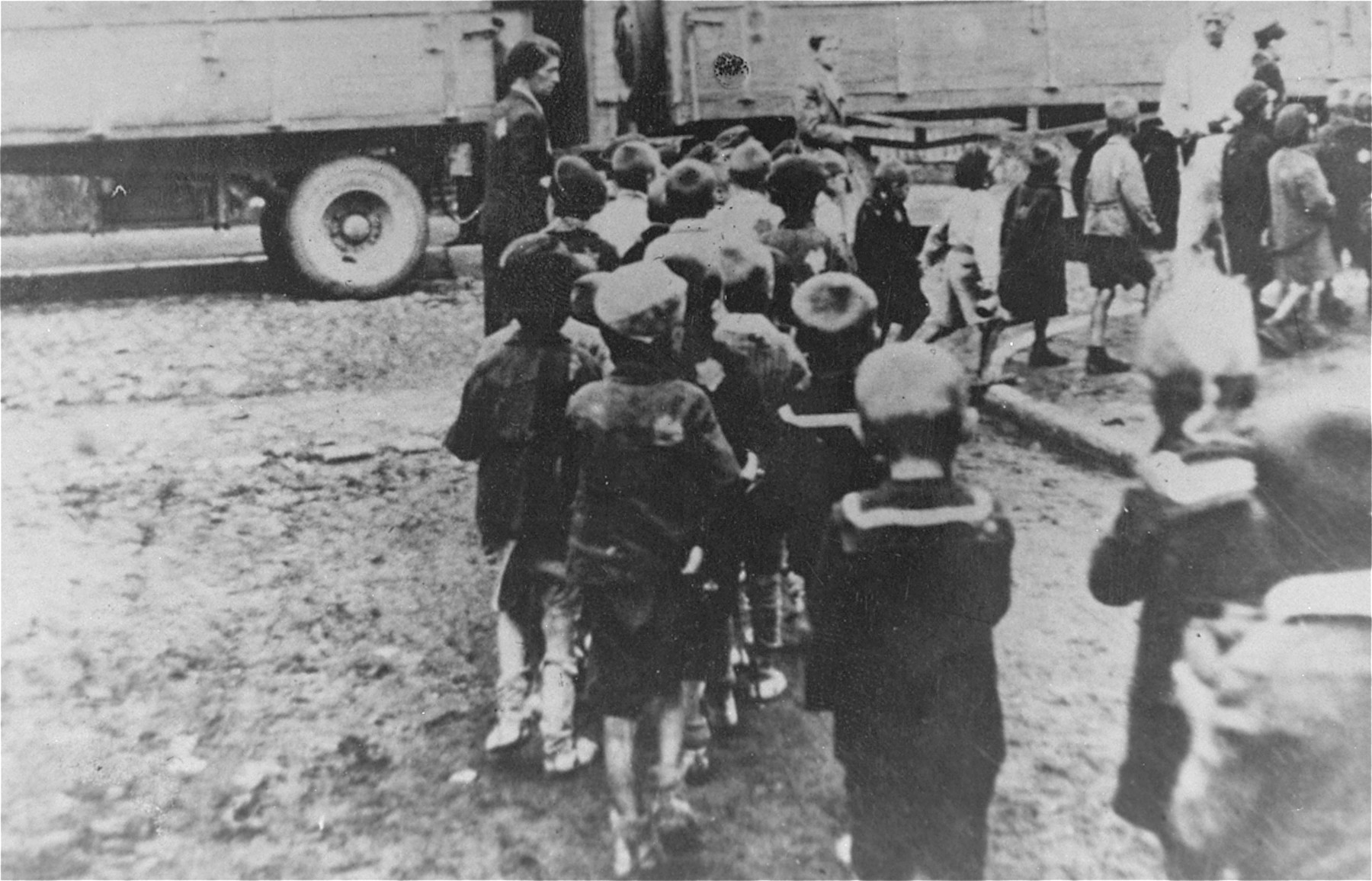 Children from the Marysin colony who were rounded-up during the "Gehsperre" action in the Lodz ghetto, walk in a line to the trucks that will transport them out of the ghetto.