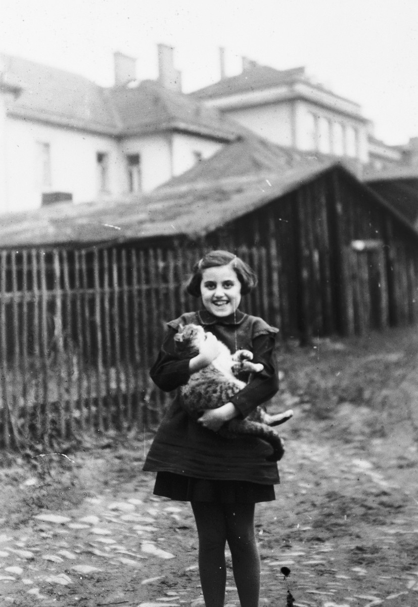 Kitty Weichherz stands by a fence holding a cat [perhaps in Cadca].

This photo was taken from the diary of Kitty's life written by her father, Bela Weichherz.