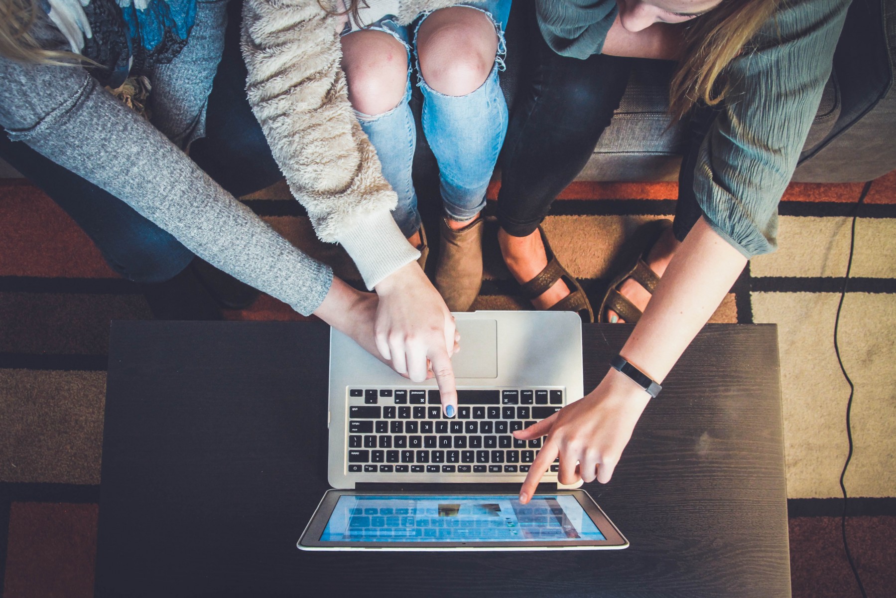 Group of people looking at a laptop on a table.