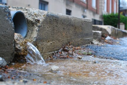 Storm drain sends water into a road, which will lead to the Bay.