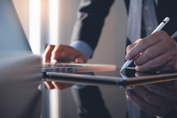 Businessman using stylus pen signing contract on digital tablet working on laptop computer in modern office, electronic signature. Business man taking note on touchpad, business and technology concept