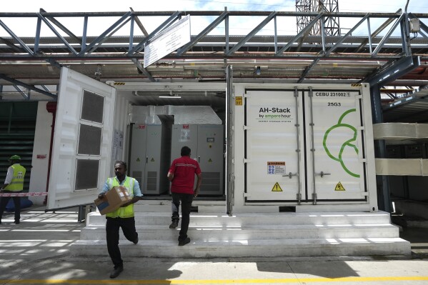 A worker walks in front of the 500-kilowatt battery energy storage system inside the Hindustan Coca-Cola Beverages factory in Thiruvallur district, on the outskirts of Chennai, India, Tuesday, July 16, 2024. (AP Photo/Mahesh Kumar A.)