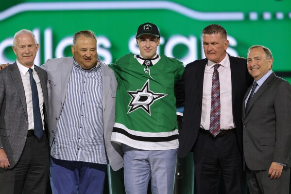 Emil Hemming, center, poses after being selected by the Dallas Stars during the first round of the NHL hockey draft Friday, June 28, 2024, in Las Vegas. (AP Photo/Steve Marcus)