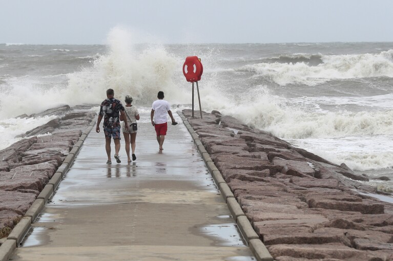 People watch waves crash into the 37th Street rock groin in Galveston, Texas on Sunday, July 7, 2024, as Tropical Storm Beryl churns toward the Texas Coast. (Jennifer Reynolds/The Galveston County Daily News via AP)