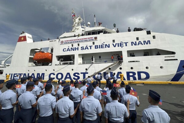 Philippine Coast Guard personnel wave Vietnamese and Filipino flags to welcome the Vietnam Coast Guard (VCG) ship, CSB 8002, in Manila, Philippines, Monday, Aug. 2024. (AP Photo/Joeal Calupitan)