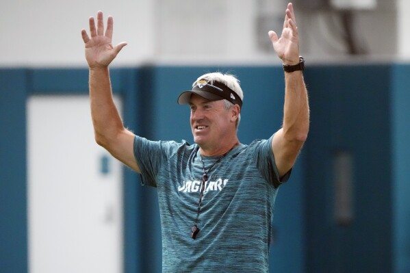 Jacksonville Jaguars head coach Doug Pederson jokes with players as he signals a touchdown during a pass drill at the team's NFL football practice, Tuesday, June 11, 2024, in Jacksonville, Fla. (AP Photo/John Raoux)