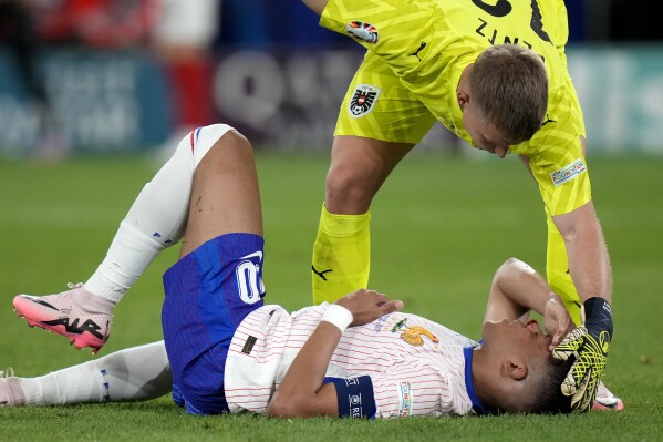 Kylian Mbappe of France receives a treatment after suffering an injury during a Group D match between Austria and France at the Euro 2024 soccer tournament in Duesseldorf, Germany, Monday, June 17, 2024. (AP Photo/Alessandra Tarantino)