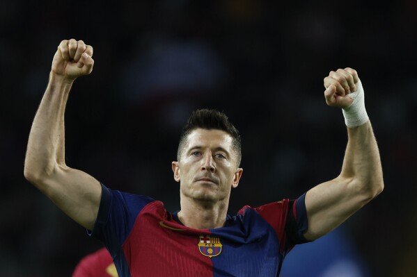 Barcelona's Robert Lewandowski celebrates after scoring the opening goal from the penalty spot during a Spanish La Liga soccer match between Barcelona and Sevilla at the Olimpic Lluis Companys stadium in Barcelona, Spain, Sunday, Oct. 20, 2024. (AP Photo/Joan Monfort)