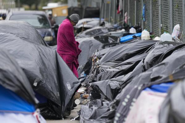 A migrant stands in the cold weather at a makeshift camp on the U.S.-Mexico border in Matamoros, Mexico, Friday, Dec. 23, 2022. Migrants are waiting on a pending U.S. Supreme Court decision on asylum restrictions. (AP Photo/Fernando Llano)