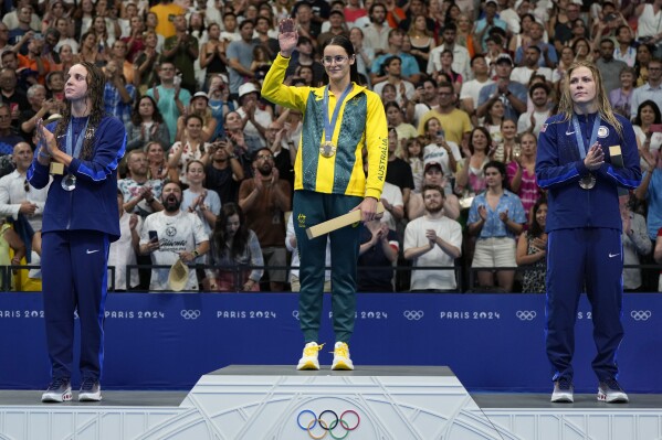 CAPTION CORRECTS SPELLING Gold medalist Australia's Kaylee McKeown, centre, stands with silver medalist, Regan Smith of the United States, left, and bronze medalist Katharine Berkoff of the United States on the podium following women's 100-meter backstroke final at the 2024 Summer Olympics, Monday, Tuesday, July 30, 2024. (AP Photo/Matthias Schrader)