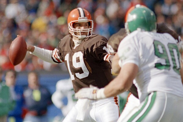 FILE - Cleveland Brown's quarterback Bernie Kosar (19) winds up to throw in the first quarter as Philadelphia Eagles defensive tackle Mike Golic (90) rushes during an NFL football game in Cleveland, Nov. 10, 1991. The former Browns great is in “the fight of his life” dealing with liver failure and the early stages of Parkinson’s disease, Cleveland Magazine reports. (AP Photo/Jeff Haynes, File)
