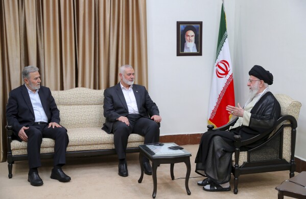 In this photo released by an official website of the office of the Iranian supreme leader, Supreme Leader Ayatollah Ali Khamenei, right, speaks with Hamas chief Ismail Haniyeh, center, and the leader of the Palestinian Islamic Jihad group Ziad Nakhaleh in a meeting in Tehran, Iran, Tuesday, July 30, 2024. (Office of the Iranian Supreme Leader via AP)