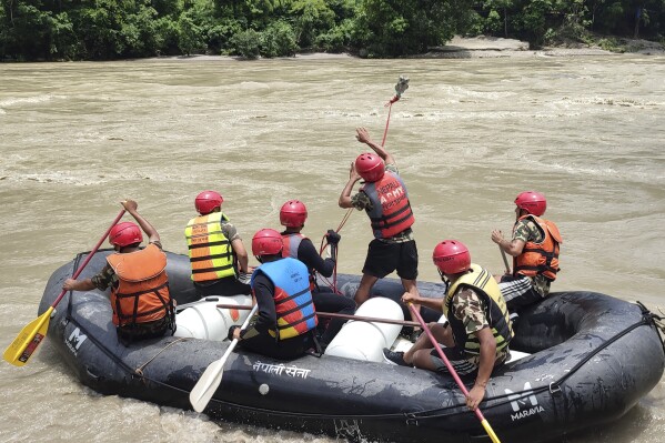 Nepal army personnel cary out a search operation looking for the survivors after two buses were swept by a landslide off the highway and into a swollen river near Simaltal, about 120 kilometers (75 miles) west of the capital Kathmandu, Nepal, Saturday, July 13, 2024. (AP Photo/ Ramesh Paudel)