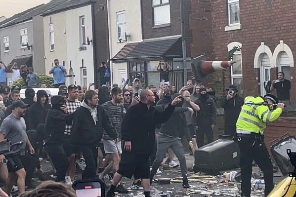 An unruly crowd clash with police, Tuesday, July 30, 2024, in Southport, northwest England, near where three girls were stabbed to death in a dance class the day before. The violence erupted shortly after a peaceful vigil was attended by hundreds in the center of Southport to mourn the 13 victims of the stabbings, including seven still in critical condition. (Richard McCarthy/PA via AP)