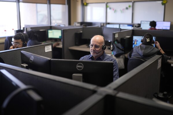 Customer Experience Representatives Stanley Solis, center, and other representatives take calls at an Alorica center, Monday, Aug. 19, 2024, in San Antonio. (AP Photo/Eric Gay)