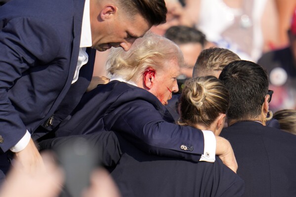 Republican presidential candidate former President Donald Trump is helped off the stage at a campaign event in Butler, Pa., on Saturday, July 13, 2024. (AP Photo/Gene J. Puskar)