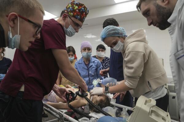 FILE - Nurse Dmytro Gavro, left, with his colleagues perform CPR on a girl fatally injured during the shelling of a residential area, in the city hospital of Mariupol, eastern Ukraine, Sunday, Feb. 27, 2022. A team of doctors and nurses who fled Mariupol as Russian forces closed in on their hospital are starting up a new medical center in the Ukrainian capital to serve people displaced by the war. Around 30 staff from Mariupol's Hospital Number 2 and a team of cardiac specialists who rescued their equipment from shelling in the eastern city of Kramatorsk started taking patients on Tuesday, Dec. 13, 2022. (AP Photo/Evgeniy Maloletka, File)