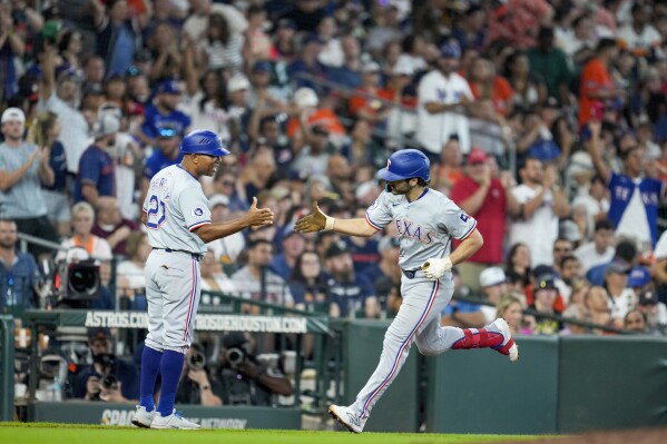 Texas Rangers' Josh Smith, right, celebrates his two-run home run against the Houston Astros with third base coach Tony Beasley during the eighth inning of a baseball game, Sunday, July 14, 2024, in Houston. (AP Photo/Eric Christian Smith)