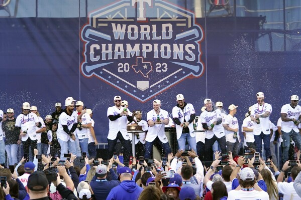 FILE - The Texas Rangers, on stage, spray champagne on fans during a World Series baseball championship celebration, Friday, Nov. 3, 2023, in Arlington, Texas. (AP Photo/Julio Cortez, File)