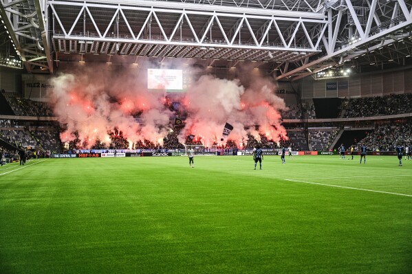 Djurgarden supporters set off pyrotechnics during the Allsvenskan soccer match between Hammarby IF and Djurgardens IF at Tele 2 Arena in Stockholm, Sweden on Sunday, Oct. 20, 2024. (Magnus Lejhall/TT News Agency via AP)