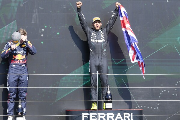 Mercedes driver Lewis Hamilton of Britain celebrates on the podium with second placed Red Bull driver Max Verstappen of the Netherlands, left, after winning the British Formula One Grand Prix race at the Silverstone racetrack, Silverstone, England, Sunday, July 7, 2024. (AP Photo/Luca Bruno)