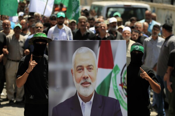 Hamas members hold a poster of Hamas political chief Ismail Haniyeh during a protest to condemn his killing, at al-Bass Palestinian refugee camp, in the southern port city of Tyre, Lebanon, Wednesday, July 31, 2024. Haniyeh, Hamas' political chief in exile who landed on Israel's hit list after the militant group staged its surprise Oct. 7 attacks, was killed in an airstrike in the Iranian capital early Wednesday. (AP Photo/Mohammed Zaatari)