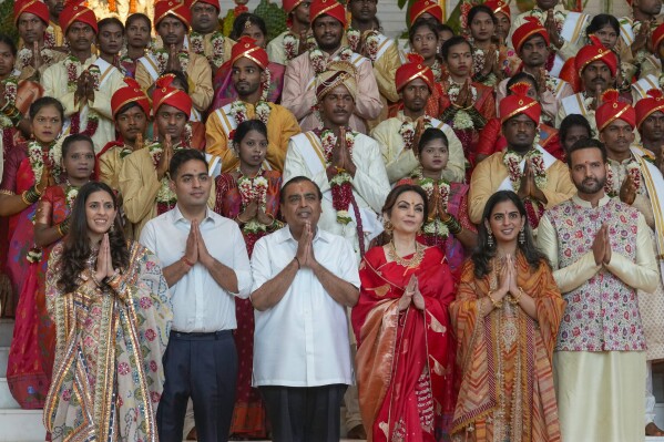 FILE - Chairman of Reliance Industries Limited Mukesh Ambani, third left, poses with his family members and underprivileged couples during a mass wedding organized by him as the part of pre-wedding celebrations of his youngest son, Anant Ambani, in Mumbai, India, Tuesday, July 2, 2024. (AP Photo/Rafiq Maqbool, File)