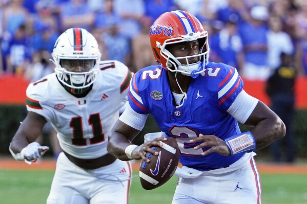 Florida quarterback DJ Lagway (2) looks for a receiver as he is chased by Miami defensive lineman Elijah Alston (11) during the second half of an NCAA college football game, Saturday, Aug. 31, 2024, in Gainesville, Fla. (AP Photo/John Raoux)