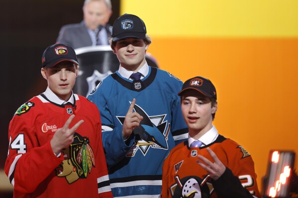Artyom Levshunov, left, second overall pick of the Chicago Blackhawks; Macklin Celebrini, center, first overall pick of the San Jose Sharks; and Beckett Sennecke, third overall pick of the Anaheim Ducks, pose during the first round of the NHL hockey draft Friday, June 28, 2024, in Las Vegas. (AP Photo/Steve Marcus)