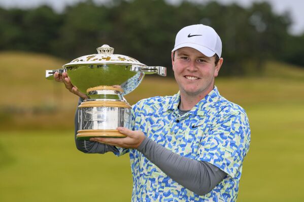 Robert MacIntyre poses with the Genesis Scottish Open trophy after he wins the Genesis Scottish Open 2024 golf tournament in North Berwick, Scotland, Sunday July 14, 2024. (Malcolm Mackenzie/PA via AP)