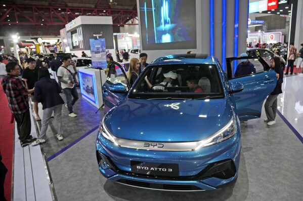 People inspect electric vehicles made by Chinese automaker BYD during an auto fair in Jakarta, Indonesia, Wednesday, June 19, 2024. Investment in electric vehicle manufacturing is booming in Morocco, a country that neighbors Europe and enjoys a free trade agreement with the United States. That's partially because Chinese firms see it as a side door to access the U.S. market and new Biden administration subsidies designed to shut them out. (AP Photo/Achmad Ibrahim)