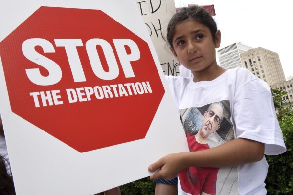 FILE - Eight-year-old Khloe Marogi, of West Bloomfield, Mich., wears a t-shirt with her detained father's photo on it at a rally outside the Patrick V. McNamara Federal Building Friday, June 16, 2017, in Detroit to protest the recent Immigration and Customs Enforcement raids in which 114 Iraqi nationals in Metro Detroit were detained and are facing deportation, June 16, 2017. A judge approved a settlement Wednesday, July 31, 2024 in a 2017 lawsuit that challenged the detention of Iraqi nationals who were targeted for deportation during the Trump administration. (Tanya Moutzalias/MLive Detroit via AP)