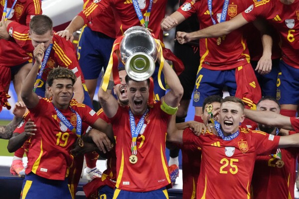 Spain's Alvaro Morata holds the trophy as he celebrates with his teammates after winning the final match between Spain and England at the Euro 2024 soccer tournament in Berlin, Germany, Sunday, July 14, 2024. Spain won 2-1. (AP Photo/Frank Augstein)