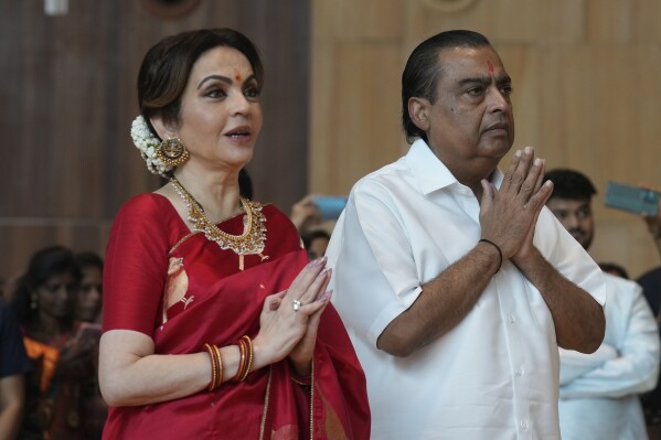 Chairman of Reliance Industries Limited Mukesh Ambani, right, along with his wife Nita Ambani, greets underprivileged couples during a mass wedding organized by them as the part of pre-wedding celebrations of their youngest son, Anant Ambani in Navi Mumbai, India, Tuesday, July 2, 2024. (AP Photo/Rafiq Maqbool)