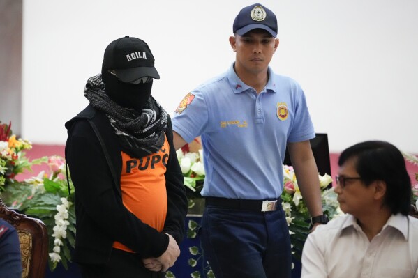 Apollo Quiboloy, left, a Filipino preacher accused of sexual abuse and human trafficking in the Philippines and similar charges in the United States, is escorted as Philippine Secretary of Interior and Local Government Benhur Abalos, right, looks on during a press conference at the Camp Crame police headquarters in Quezon City, Philippines Monday, Sept. 9, 2024. (AP Photo/Aaron Favila)