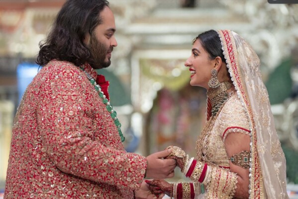 In this photo provided by Reliance Industries, Anant Ambani, left, the son of billionaire Mukesh Ambani, holds hands with Radhika Merchant during their wedding ceremony at Jio World Convention Centre in Mumbai, India, Friday, July 12, 2024. (Reliance Industries via AP)