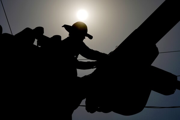 FILE - A linesman works on power lines under the morning sun, July 12, 2024, in Phoenix. On Wednesday, July 31, 2024, the Labor Department reports on wages and benefits for U.S. workers during the second quarter of 2024.(AP Photo/Matt York)